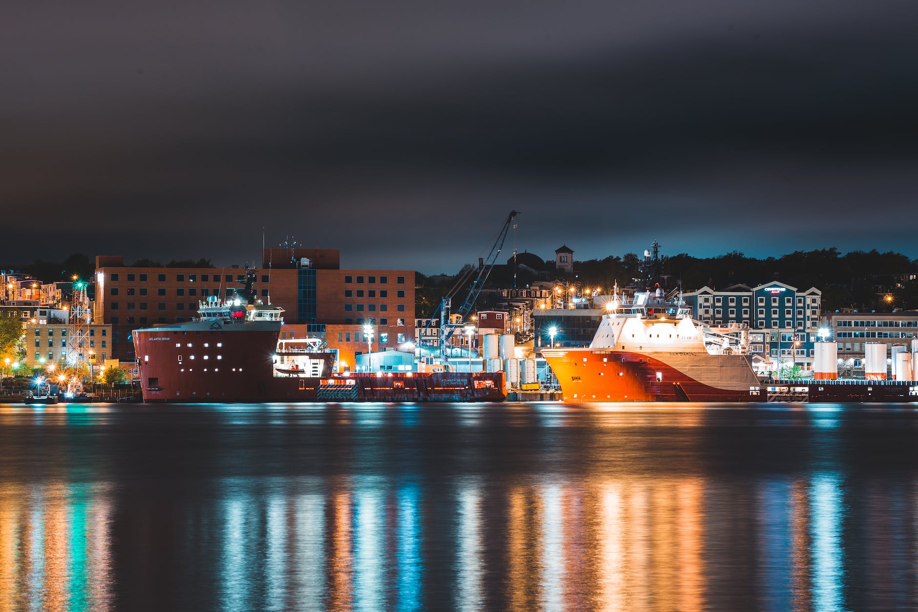 ships moored in port of modern city at night